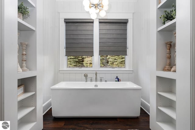 bathroom featuring a soaking tub, built in shelves, and wood finished floors