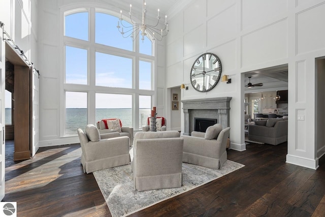 living room with a barn door, a fireplace, an inviting chandelier, dark wood-style floors, and a decorative wall