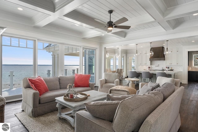 living area with dark wood-style floors, beamed ceiling, ceiling fan, and ornamental molding