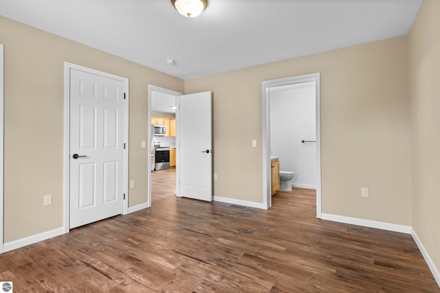 unfurnished bedroom featuring connected bathroom, visible vents, baseboards, and dark wood finished floors