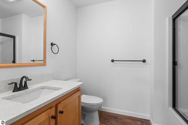 full bathroom featuring a shower with door, baseboards, toilet, wood finished floors, and vanity