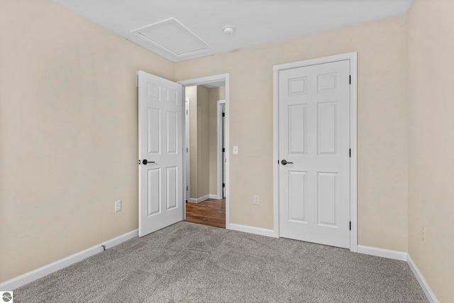 unfurnished bedroom featuring baseboards, carpet floors, and attic access