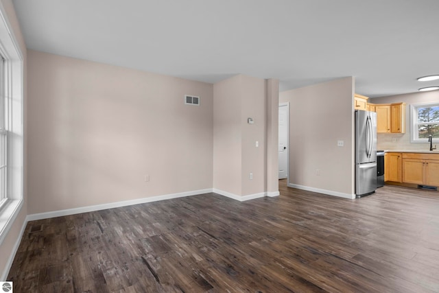 unfurnished living room featuring baseboards, visible vents, dark wood-style flooring, and a sink