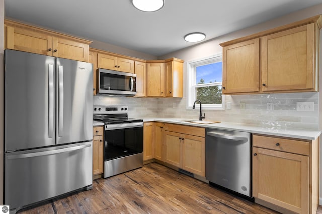 kitchen featuring light brown cabinetry, dark wood-type flooring, appliances with stainless steel finishes, and a sink