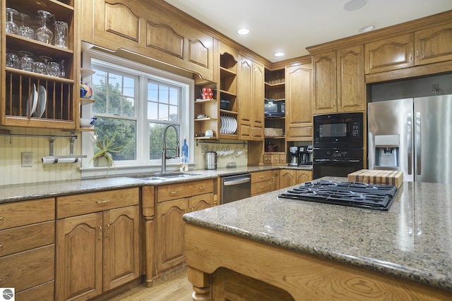 kitchen with black appliances, light stone counters, open shelves, and a sink