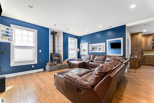 living area featuring light wood-style flooring, recessed lighting, a healthy amount of sunlight, and a wood stove