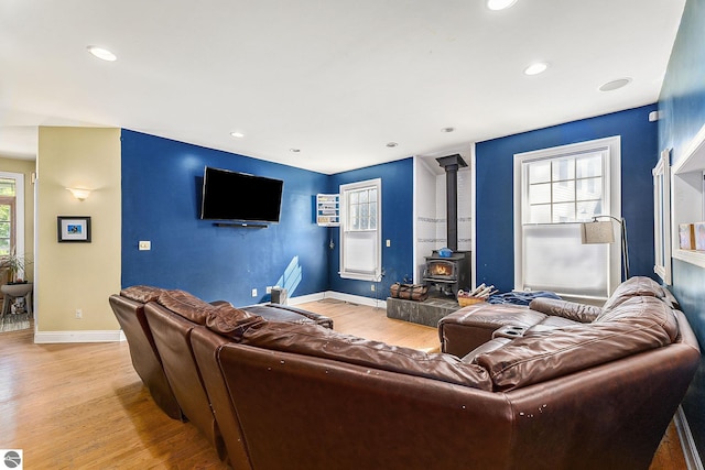 living room with a wood stove, recessed lighting, baseboards, and light wood finished floors