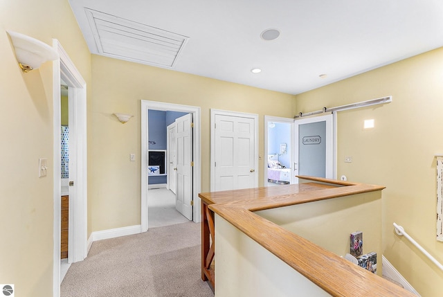 hall with visible vents, baseboards, light colored carpet, a barn door, and recessed lighting