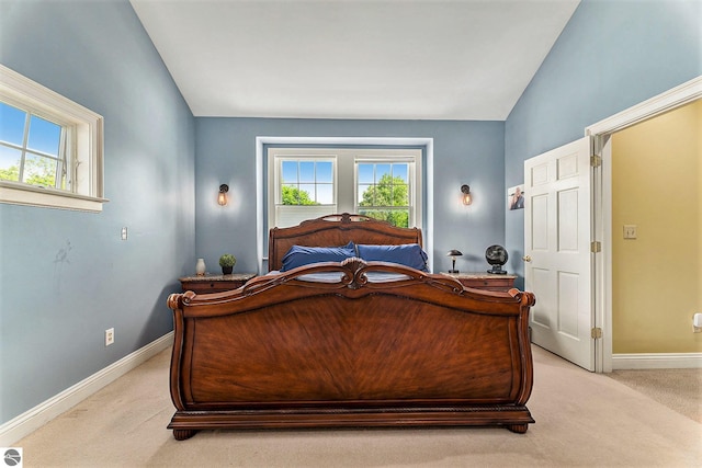 bedroom featuring baseboards, multiple windows, light carpet, and vaulted ceiling