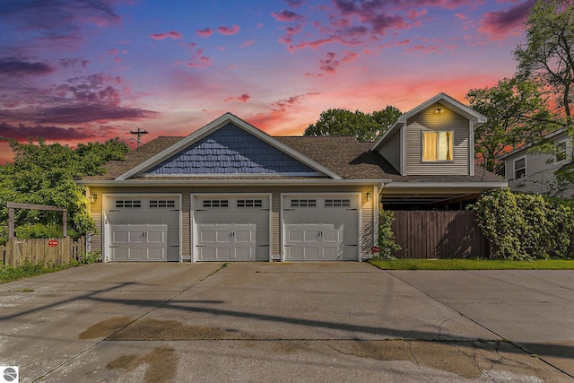 view of front facade featuring driveway, a shingled roof, and fence