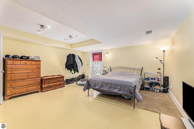 bedroom with a tray ceiling, visible vents, and baseboards