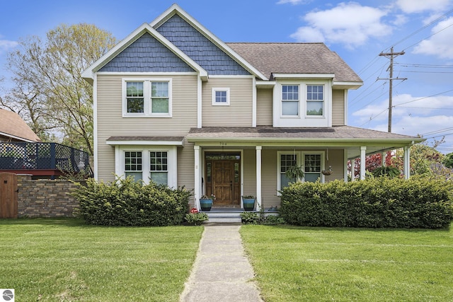 view of front of property featuring a front lawn, covered porch, and roof with shingles