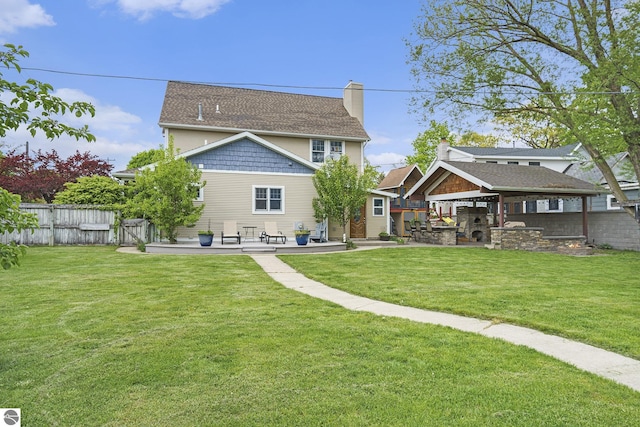 back of property featuring fence, a lawn, and a patio area