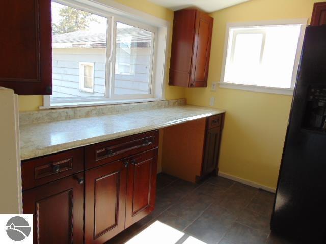 kitchen with baseboards, black refrigerator with ice dispenser, and light countertops