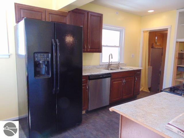 kitchen with a sink, dishwasher, black refrigerator with ice dispenser, and light countertops