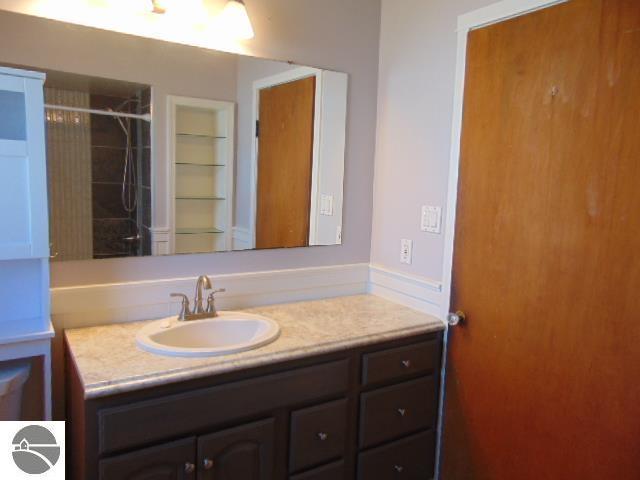 full bathroom with tiled shower and vanity