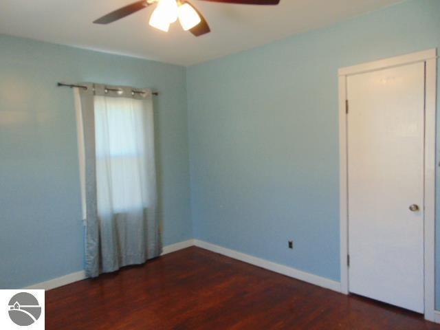 spare room featuring baseboards, wood finished floors, and a ceiling fan