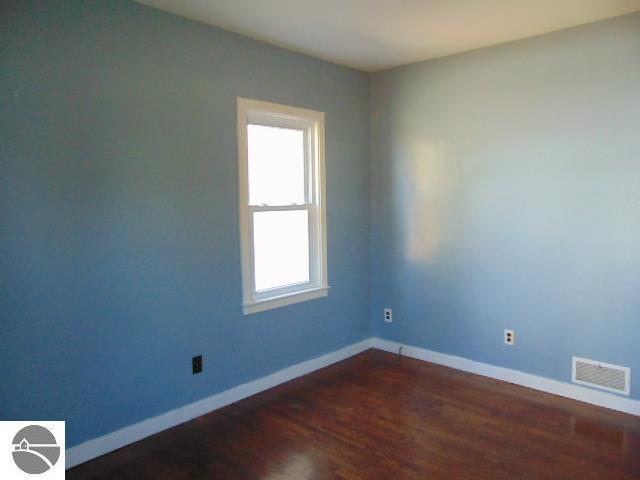 empty room with visible vents, baseboards, and dark wood-style flooring