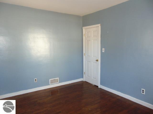 spare room featuring visible vents, baseboards, and wood finished floors