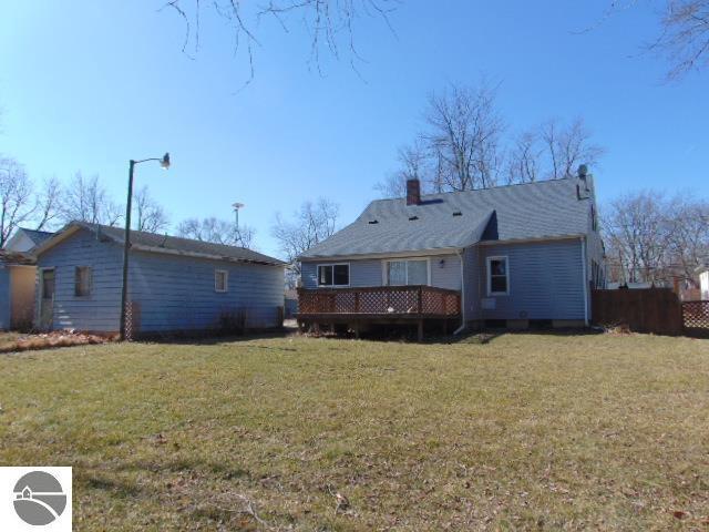 rear view of house featuring a lawn, a chimney, and a deck