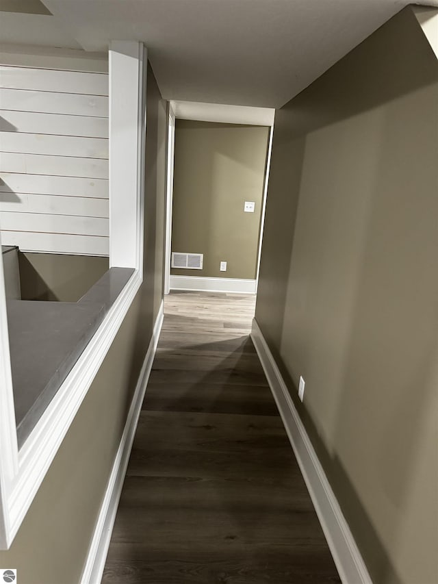 hallway with visible vents, baseboards, and wood finished floors