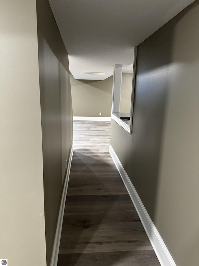 corridor featuring baseboards and dark wood finished floors