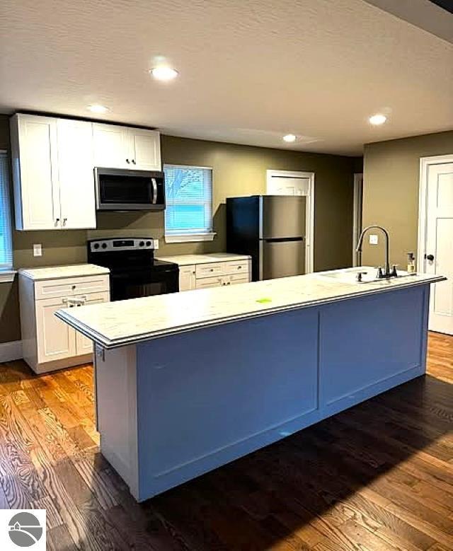 kitchen featuring wood finished floors, stainless steel appliances, light countertops, and a sink