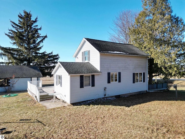 back of house featuring a yard, roof with shingles, and a wooden deck