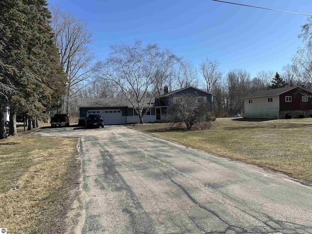 single story home with a chimney, a front lawn, concrete driveway, and a garage