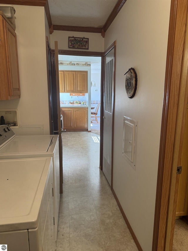 clothes washing area with baseboards, cabinet space, crown molding, and washing machine and clothes dryer