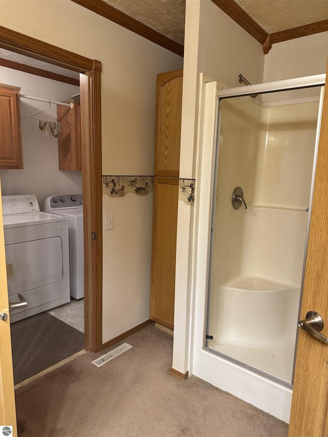 full bath featuring visible vents, ornamental molding, a stall shower, washer and dryer, and a textured ceiling