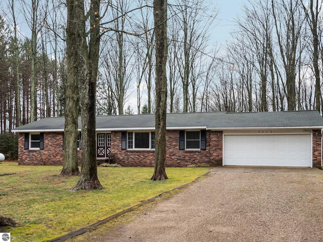 ranch-style house featuring a front yard, an attached garage, brick siding, and driveway