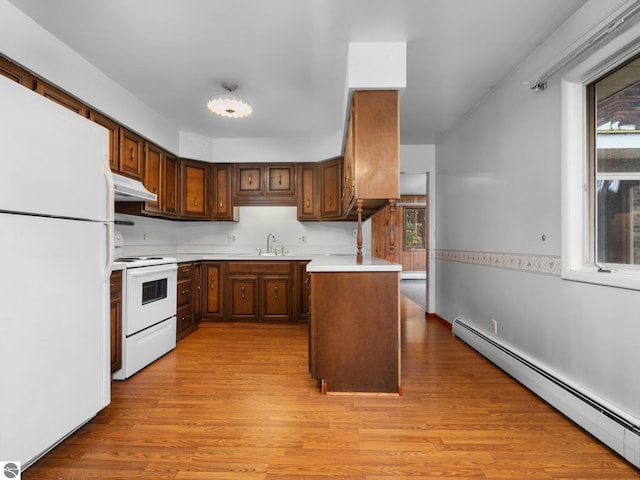 kitchen with under cabinet range hood, light countertops, light wood-style flooring, white appliances, and a baseboard radiator