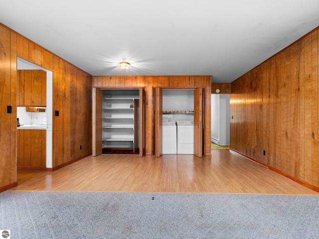 empty room with wooden walls, light carpet, independent washer and dryer, and light wood-type flooring