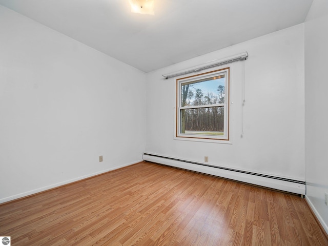 spare room with a baseboard heating unit, light wood-style flooring, and baseboards