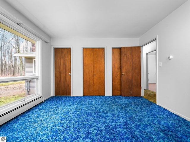 unfurnished bedroom with two closets, carpet flooring, and baseboard heating