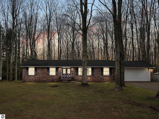 ranch-style house featuring brick siding, a front yard, an attached garage, and driveway