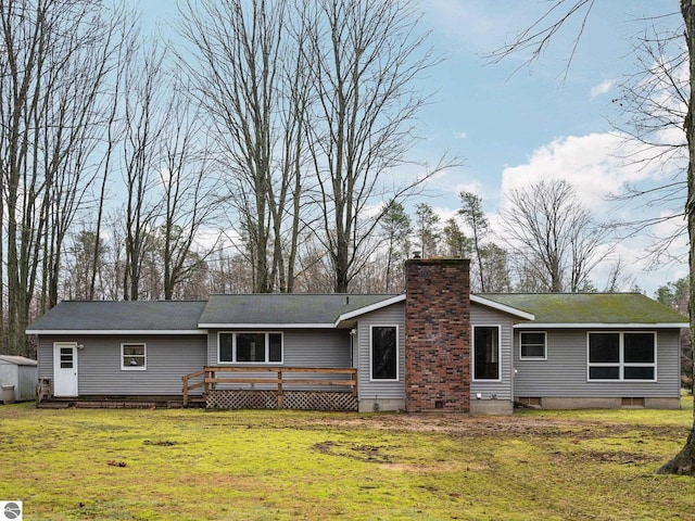 view of front of home with a wooden deck, a chimney, and a front lawn