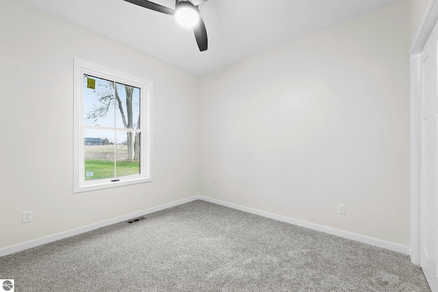 carpeted empty room with visible vents, ceiling fan, and baseboards