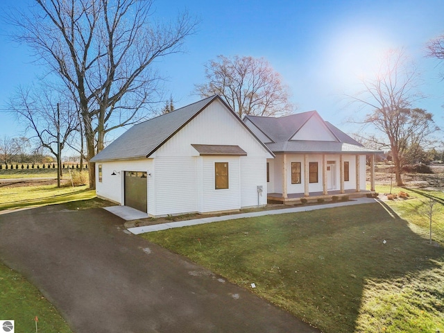 modern inspired farmhouse with a front yard, roof with shingles, a porch, an attached garage, and aphalt driveway