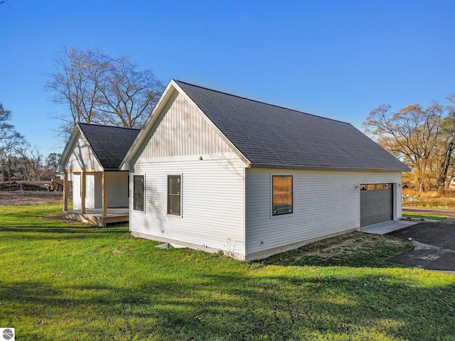 view of side of home with a lawn, a shingled roof, and a garage