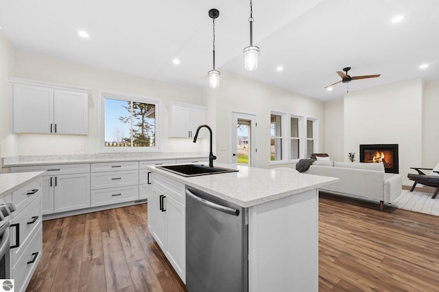 kitchen featuring a sink, dark wood-type flooring, stainless steel dishwasher, a glass covered fireplace, and a kitchen island with sink