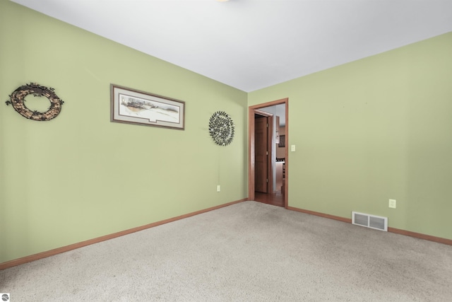 carpeted spare room with visible vents and baseboards