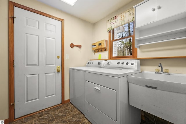 washroom featuring washer and dryer, baseboards, stone finish floor, and a sink