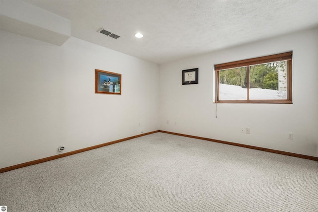 carpeted spare room featuring visible vents, baseboards, and a textured ceiling