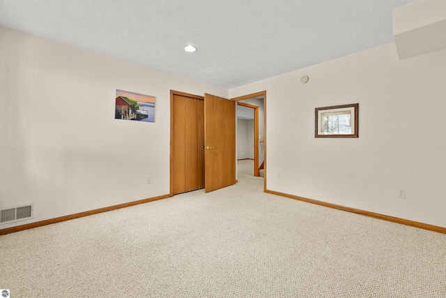 empty room with visible vents, light colored carpet, and baseboards