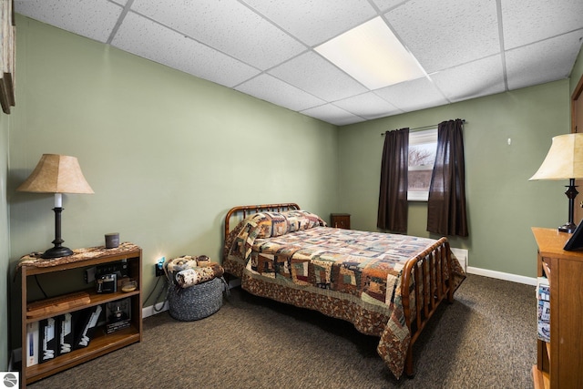 bedroom featuring a drop ceiling, baseboards, and carpet