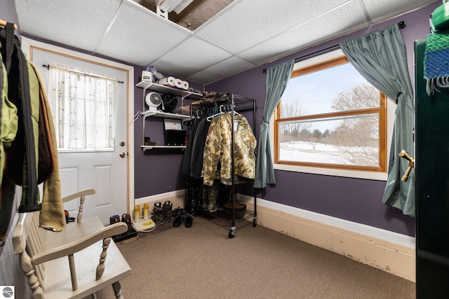 interior space featuring a paneled ceiling, baseboards, and carpet floors