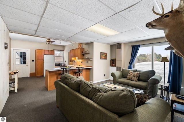 living room with visible vents, baseboards, dark carpet, rail lighting, and a paneled ceiling