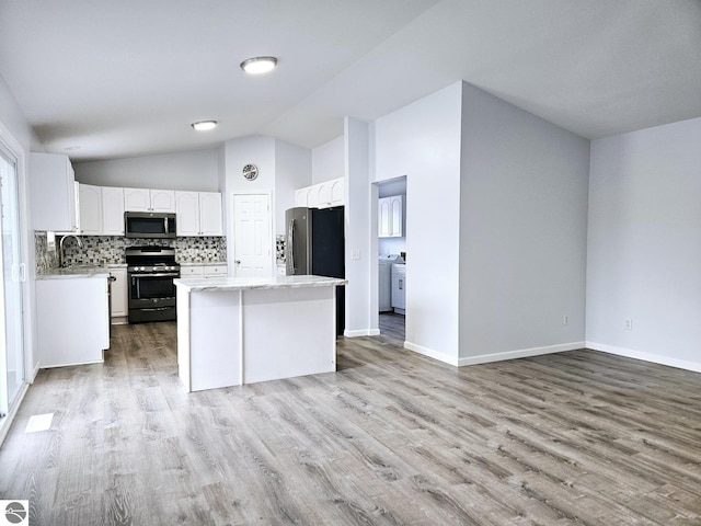 kitchen with a kitchen island, light wood-type flooring, decorative backsplash, appliances with stainless steel finishes, and white cabinets